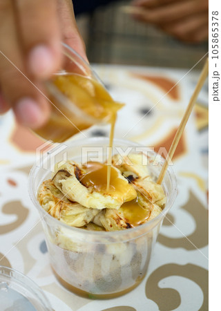 Grilled banana eating with coconut caramel sauce, Traditional Thai dessert Grilled banana eating with coconut caramel sauce, Traditional Thai dessert 105865378