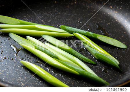 にんにくの芽(斜め切り)をフライパンで炒める調理シーン。 にんにくの芽(斜め切り)をフライパンで炒める調理シーン。 105865990