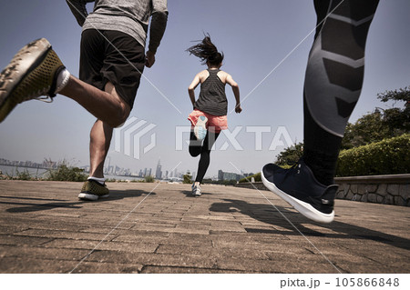 three young asian adults running jogging outdoors, rear and low angle view 105866848