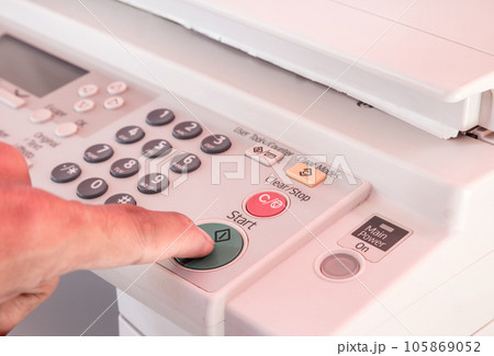 Hand pressing Start button on copy machine 105869052