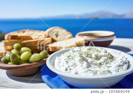 Close up view of tzatziki on Greek table, sea in background. Close up view of tzatziki on Greek table, sea in background. 105869249