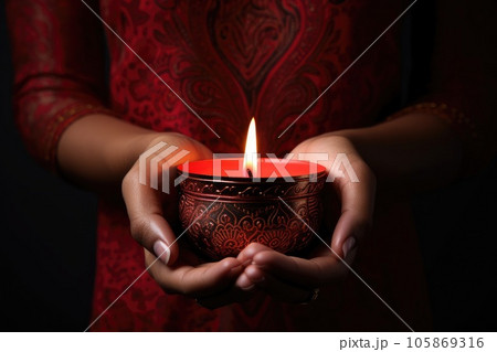 Woman hands with henna holding colorful clay diya lamps lit during diwali celebration Woman hands with henna holding colorful clay diya lamps lit during diwali celebration 105869316