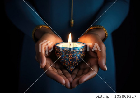 Woman hands with henna holding colorful clay diya lamps lit during diwali celebration Woman hands with henna holding colorful clay diya lamps lit during diwali celebration 105869317