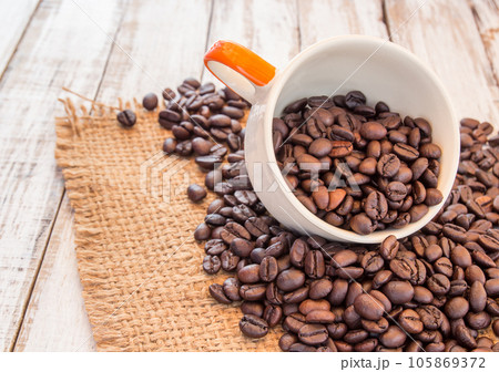 Coffee beans and coffee cup on wooden background Coffee beans and coffee cup on wooden background 105869372