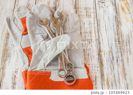Leather work gloves and wrench on wooden table 105869623