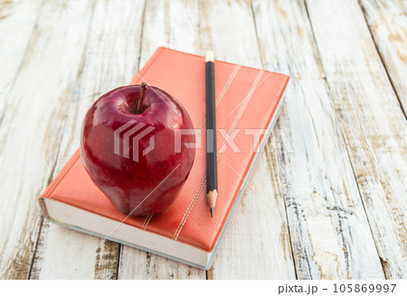 Red apple and pencil on notebook on white wooden table Red apple and pencil on notebook on white wooden table 105869997