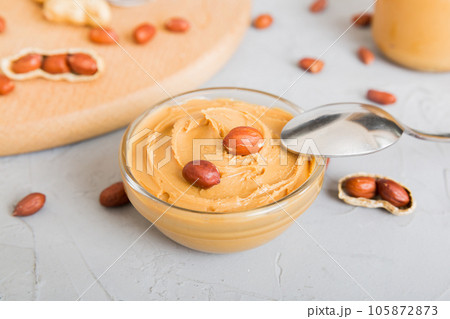 Bowl of peanut butter and peanuts on table background. top view with copy space. Creamy peanut pasta in small bowl 105872873