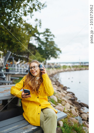 Young woman listens to music, podcast outdoors. Communication in social networks. Lifestyle. 105873062