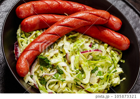 cooked sausages with coleslaw salad in black bowl cooked sausages with coleslaw salad in black bowl 105873321