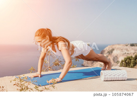 Fitness woman sea. Outdoor workout on yoga mat roller in park near to ocean beach. Female fitness pilates yoga routine concept. Healthy lifestyle. Happy fit woman exercising with rubber band in park. Fitness woman sea. Outdoor workout on yoga mat roller in park near to ocean beach. Female fitness pilates yoga routine concept. Healthy lifestyle. Happy fit woman exercising with rubber band in park. 105874067