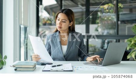 Asian businesswomen sit at their desks and calculate financial graphs showing results about their investments, planning successful business growth process 105874068