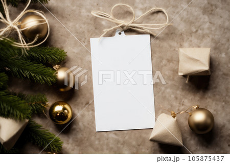 A mock-up of a white tag card with a gift box and a garland with Christmas tree toys and cones 105875437