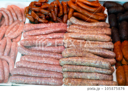 Different types of sausages laid out in showcase of butcher shop 105875876