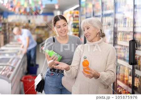 Mom with adult daughter choose and buy bottles of carbonated drink in supermarket 105875976
