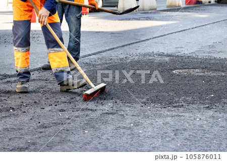 Workers repair the road around sewer manholes on a summer day. Workers repair the road around sewer manholes on a summer day. 105876011