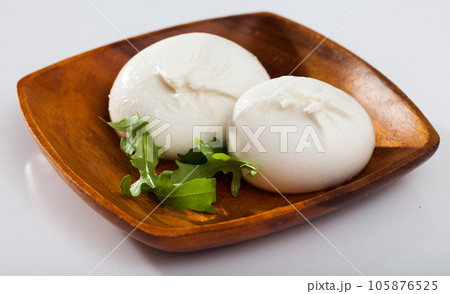 Burrata italian white cheese and arugula leaf closeup Burrata italian white cheese and arugula leaf closeup 105876525