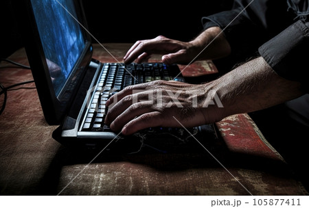 Hacker or programmer uses his computer in a dark room or basement 105877411