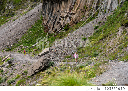 Mountain trekking. Hiker with trekking sticks climbs steep on mountain trail. Mountain landscape. Tourism, sport life style concept 105881050
