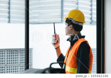 Young Asian engineer talking radio walkie talkie to operate and control the worker employee to build construction. Young Asian engineer talking radio walkie talkie to operate and control the worker employee to build construction. 105882180