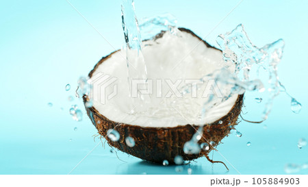 Cracked coconut with splashing water on blue background 105884903