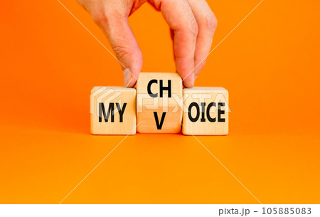 My voice and choice symbol. Businessman turns wooden cubes and changes the concept word my choice to voice. Beautiful orange table orange background, copy space. Business and my voice choice concept. 105885083