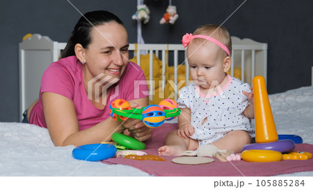 Happy young mother playing with her cute baby girl on bed at home 105885284