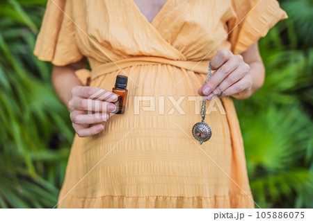 pregnant woman after 40 demonstrating the use of an aroma pendant, combining style and aromatherapy during her pregnancy journey pregnant woman after 40 demonstrating the use of an aroma pendant, combining style and aromatherapy during her pregnancy journey 105886075