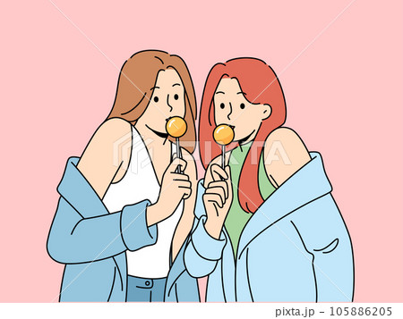 Two women with chupa chups in hands dressed in fashionable seductive clothes eat lollipops Two women with chupa chups in hands dressed in fashionable seductive clothes eat lollipops 105886205