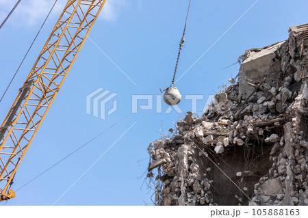 Heavy wrecking ball crane demolishing old building against blue sky in Magdeburg Germany. Building dismantling and construction waste disposal recycling service 105888163