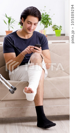 Leg injured young man suffering at home Leg injured young man suffering at home 105889294