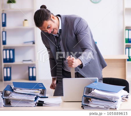 Young employee angry with excessive work holding knife Young employee angry with excessive work holding knife 105889615