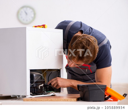 Young handsome contractor repairing fridge Young handsome contractor repairing fridge 105889934