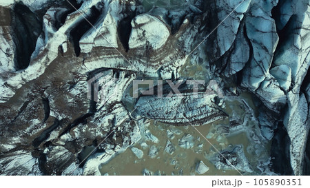 Drone shot of ice caves in iceland, massive icy rocks and dark crevasses on vatnajokull glacier cap. Diamond shaped ice mountains forming icelandic scenery with frozen water. Slow motion. 105890351