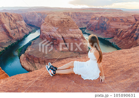Happy girl on the edge of the cliff at Horseshoe Band Canyon in Page, Arizona. Adventure and tourism concept. Beautiful nature in USA Happy girl on the edge of the cliff at Horseshoe Band Canyon in Page, Arizona. Adventure and tourism concept. Beautiful nature in USA 105890631