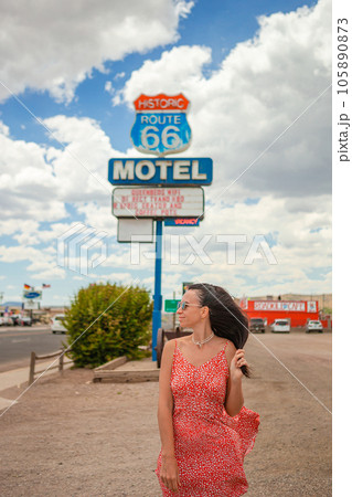 Beautiful woman in red dress on famous Highway under popular sign Route 66  105890873