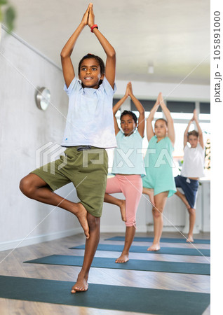 African boy stands in Tree asana, Vrikshasana. Concept of active lifestyle of young generation 105891000