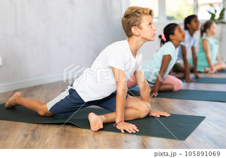 Children practicing yoga positions during group training in fitness center, performing stretching asana Urdhva Shvanasana 105891069