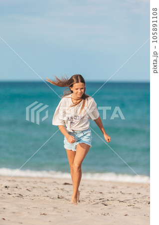 Adorable young girl enjoy tropical beach vacation. The girl on the seashore run and have fun 105891108
