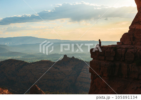 Young hiker woman on the edge of a cliff at Cathedral Rock in Sedona, Arizona. View from Scenic Cathedral Rock in Sedona with blue sky in Arizona Young hiker woman on the edge of a cliff at Cathedral Rock in Sedona, Arizona. View from Scenic Cathedral Rock in Sedona with blue sky in Arizona 105891134