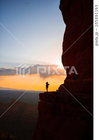 Young hiker woman on the edge of a cliff at Cathedral Rock in Sedona, Arizona. View from Scenic Cathedral Rock in Sedona with blue sky in Arizona Young hiker woman on the edge of a cliff at Cathedral Rock in Sedona, Arizona. View from Scenic Cathedral Rock in Sedona with blue sky in Arizona 105891163