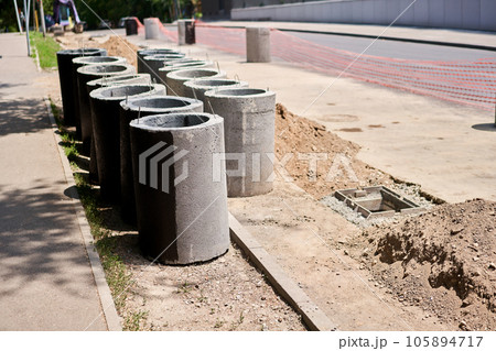 Laying concrete manholes and drain pipes for stormwater system. Connecting a trench drain to a concrete manhole structure at construction site. Construct stormwater and underground utilities Laying concrete manholes and drain pipes for stormwater system. Connecting a trench drain to a concrete manhole structure at construction site. Construct stormwater and underground utilities 105894717