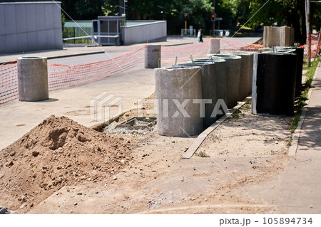 Laying concrete manholes and drain pipes for stormwater system. Connecting a trench drain to a concrete manhole structure at construction site. Construct stormwater and underground utilities Laying concrete manholes and drain pipes for stormwater system. Connecting a trench drain to a concrete manhole structure at construction site. Construct stormwater and underground utilities 105894734