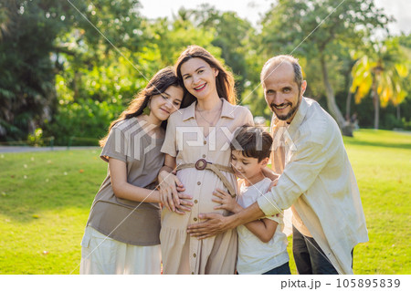 A loving family enjoying a leisurely walk in the park - a radiant pregnant woman after 40, embraced by her husband, and accompanied by their adult teenage children, savoring precious moments together A loving family enjoying a leisurely walk in the park - a radiant pregnant woman after 40, embraced by her husband, and accompanied by their adult teenage children, savoring precious moments together 105895839