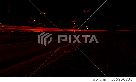 Lights of cars at night. Street line lights. Night highway city. Long exposure photograph night road. Colored bands of red light trails on the road. Background wallpaper defocused  105896836