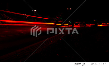 Lights of cars at night. Street line lights. Night highway city. Long exposure photograph night road. Colored bands of red light trails on the road. Background wallpaper defocused Lights of cars at night. Street line lights. Night highway city. Long exposure photograph night road. Colored bands of red light trails on the road. Background wallpaper defocused 105896837