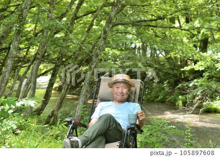 渓流のソロキャンプでコーヒーを楽しむシニア男性 105897608