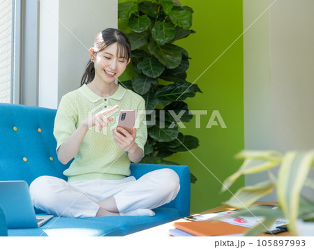 ソファに座ってスマホを操作する若い女性 105897993