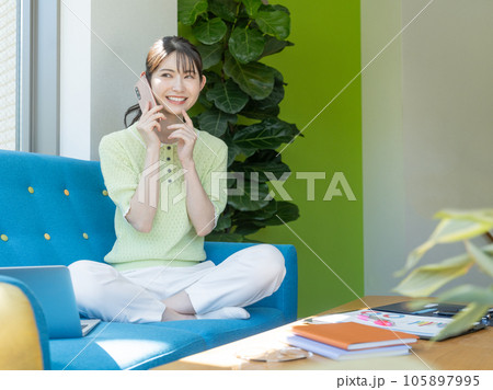 ソファに座ってスマホで会話する若い女性 105897995
