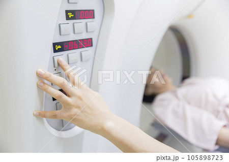 CTスキャンを操作する放射線技師手元と検査を受けるミドル女性 105898723