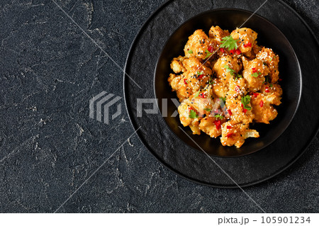 crispy orange cauliflower florets in black bowl 105901234